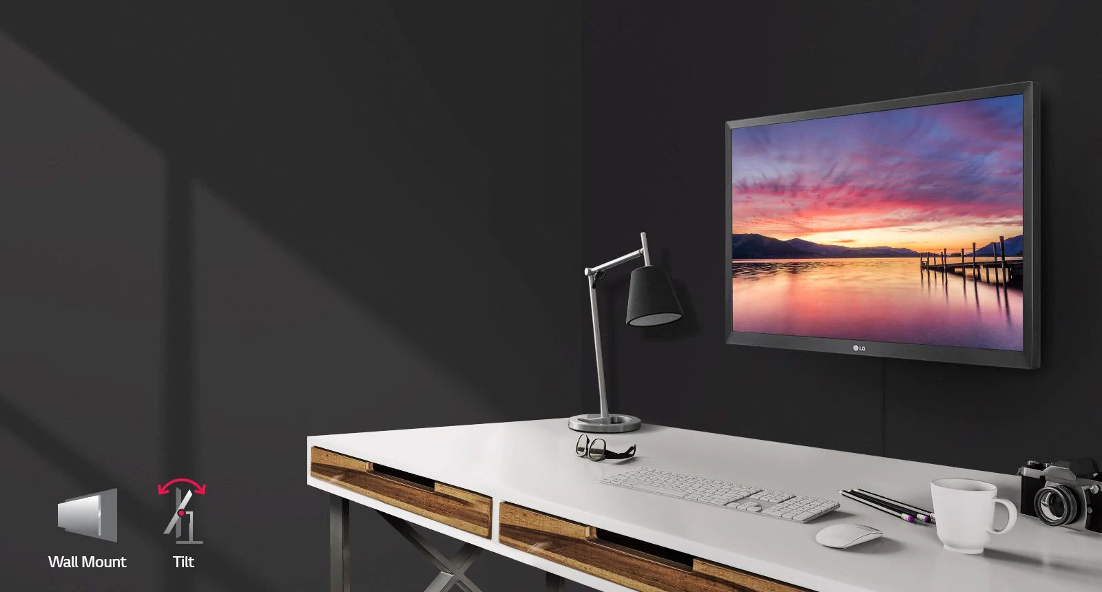 a monitor with a sunset as screen on the wall and a set of desk in front of it